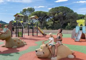 a woman and two children playing on a playground at Camping Les Cigales - Aquatique Vacances in Le Muy