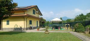 a yellow house with a gazebo in a yard at Charme rustico con ampio giardino e piscina con due camere in Carrara