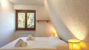 a bedroom with a white bed with a window at Hostdomus - La Tana della Volpe in Sauze d'Oulx