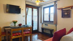 a living room with a table and a tv on the wall at Hostdomus - La Tana della Volpe in Sauze d'Oulx