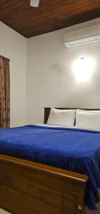a bed with a blue comforter and white pillows at VThree Hotel in Matara