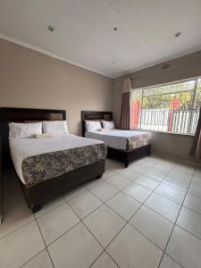 a bedroom with two beds and a window at L-PACK PRIMROSe in Germiston +65 photos