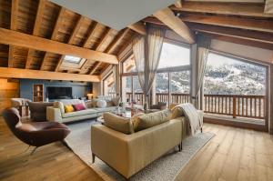 a living room with couches and chairs and windows at Falcon Lodge by Alpine Resorts in Méribel