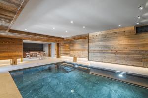 a swimming pool in a house with a wooden wall at Falcon Lodge by Alpine Resorts in Méribel