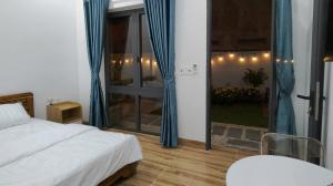 a bedroom with a bed and a window with blue curtains at Sơn Hà homestay in Ấp Bình Hưng