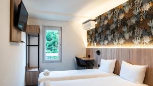 a hotel room with two beds and a tv at Kyriad ECO - Anglet Côte Basque in Anglet