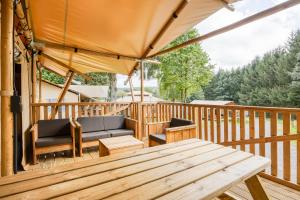 a wooden deck with a bench and a table at Camping ArdenParks La Petite Suisse - Maeva Vacansoleil in Manhay +16 photos