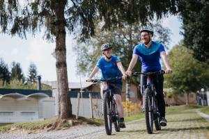a man and woman riding bikes down a road at Camping ArdenParks La Petite Suisse - Maeva Vacansoleil in Manhay