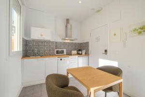 a white kitchen with a wooden table and chairs at Gorgeous Apt with a Large Private Terrace in Valencia +25 photos
