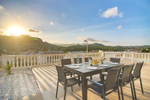 a table and chairs on a balcony with the sunset at Villas Guzman - Grandiosa in Calpe
