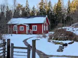 a red barn in the snow with a fence at Haus Paula in Sjötorp