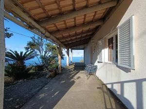 a porch of a house with chairs and a window at Casa da Volta - Porto Moniz in Porto Moniz