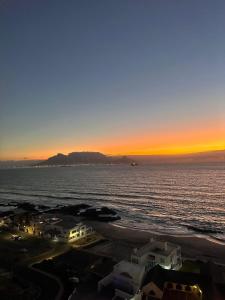 a sunset over the ocean with houses on the beach at Blouberg Heights in Cape Town