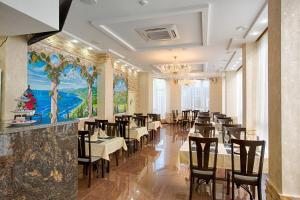 uma sala de jantar com mesas e cadeiras e um lustre em Sonata Hotel em Sochi