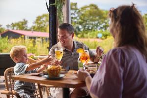a man and a woman sitting at a table with a child at RCN Vakantiepark Toppershoedje in Ouddorp