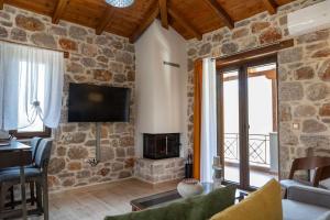 a living room with a stone wall with a tv at Elevi Mare Apartment in Tyros