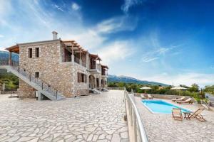 a building with a swimming pool next to a house at Elevi Mare Apartment in Tyros