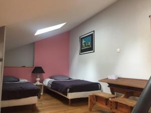 a bedroom with two beds and a table in it at Le Jardin de Norah in Brulange +3 photos