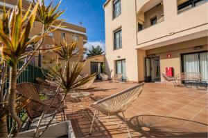 a patio with chairs and tables in a building at Castell Beach Aparthotel in Castelldefels