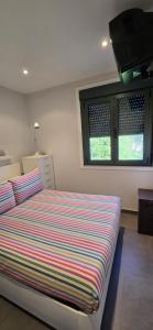 a bedroom with a bed with a striped comforter and two windows at Casa Arena 2 in Nigrán