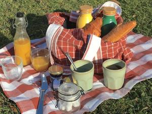 a picnic with a basket of bread and drinks on a blanket at Tentes Glamping au camping Le Gerrit à Marsous in Arrens-Marsous