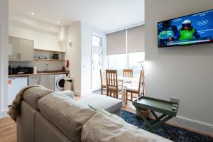 a living room with a couch and a tv on a wall at Glan Neigr Apart-Hotel by Guestz in Rhosneigr
