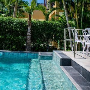 a swimming pool with two chairs and a table and a palm tree at Windy Villa by Utalay Koh Chang in Ban Khlong Son
