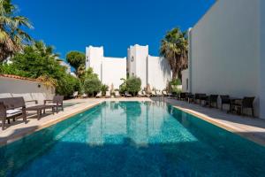 a swimming pool with chairs and a building at Porto Azul Hotel Bodrum in Bodrum City