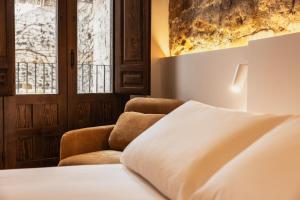 a bedroom with a bed and a chair and a window at Boutique Casa de los Pedraza in Baeza