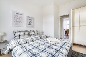 a white bedroom with a bed with a plaid blanket at Spacious Five Bedroom Central Oslo in Oslo
