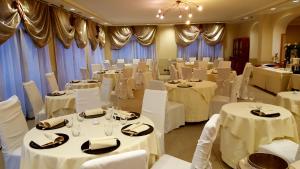 um salão de banquetes com mesas brancas e cadeiras brancas em Green Hotel em Settimo Torinese