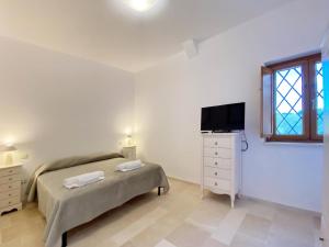 a bedroom with a bed and a tv and a dresser at Trullo al borgo in Cisternino