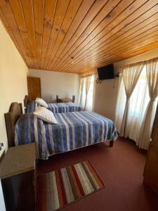 a bedroom with two beds and a flat screen tv at Residencial Golden in Los Vilos