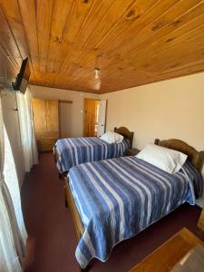 two beds in a room with wooden ceilings at Residencial Golden in Los Vilos