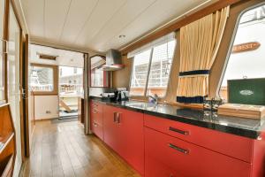 a kitchen with red cabinets and a black counter top at Authentic houseboat Amalia in Amsterdam