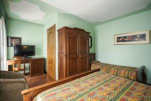 a bedroom with a bed and a cabinet and a tv at Principato Di Ariis Hotel 3 stelle Room Only in Rivignano