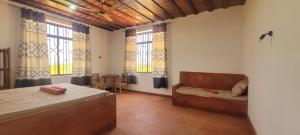 a bedroom with a bed and a couch and windows at Villa Katerina-Zanzibar Apartment Paje in Paje