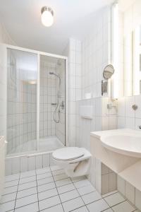 a white bathroom with a shower and a toilet and a sink at Hotel Am Dom in Bamberg