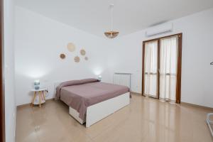 a white bedroom with a bed and a window at ilvilLINO in Taranto