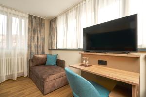 a living room with a flat screen tv and a couch at Hotel Am Dom in Bamberg