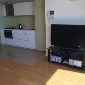 uma sala de estar com uma televisão de ecrã plano e uma cozinha em GlenelgApt em Adelaide
