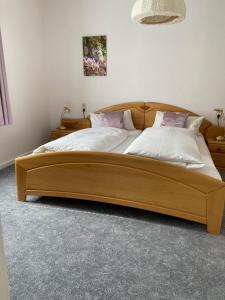 a bedroom with a wooden bed with white sheets and pink pillows at Eichhörnchenblick in Hahnenklee-Bockswiese