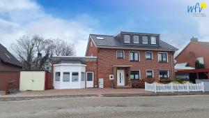 a red brick house with a white garage at Haus Wilhelm-Feldhoff Ferienwohnung Veen in Borkum