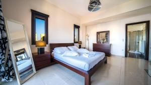 a bedroom with a bed with white sheets and a mirror at Villa Majestic Heated Pool Sauna & Endless Sea Views in Megála Khoráfia +41 photos