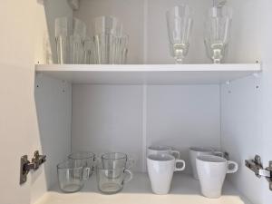 a shelf filled with glass cups and wine glasses at Central Platinum Apartments 28 z balkonem in Rybnik +28 photos