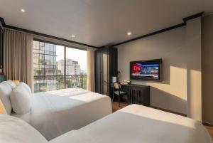 a hotel room with two beds and a television at Embrace Boutique Hanoi Hotel in Hanoi