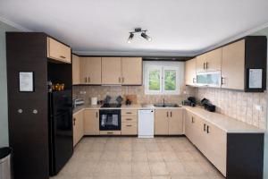 a kitchen with brown cabinets and a black refrigerator at Villa Aniley in Ratzaklíon
