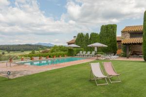 a yard with two lawn chairs and a swimming pool at Villa privada de lujo Can Riera in Pujals dels Cavallers
