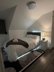 a bedroom with a bed and a nightstand with a lamp at Bpsairbnbltd in London