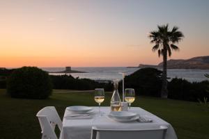 a table with two glasses of white wine and a view of the ocean at Rocca Ruja Vip in Stintino